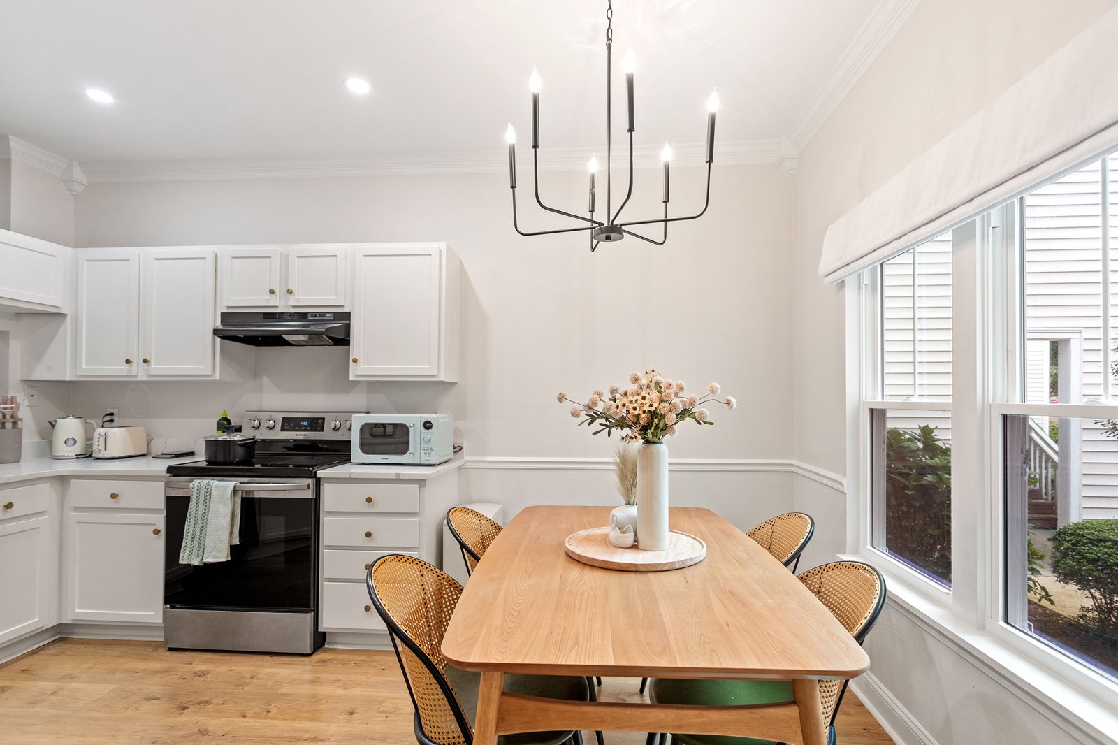 Renovated white kitchen with quartz counters and a wood dining table with cane chairs